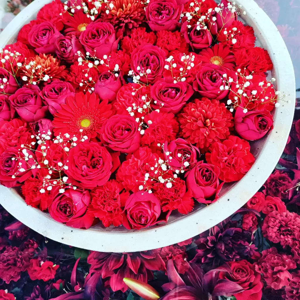 赤いバラ、赤いガーベラなどの赤い花が浮かんでいる花手水