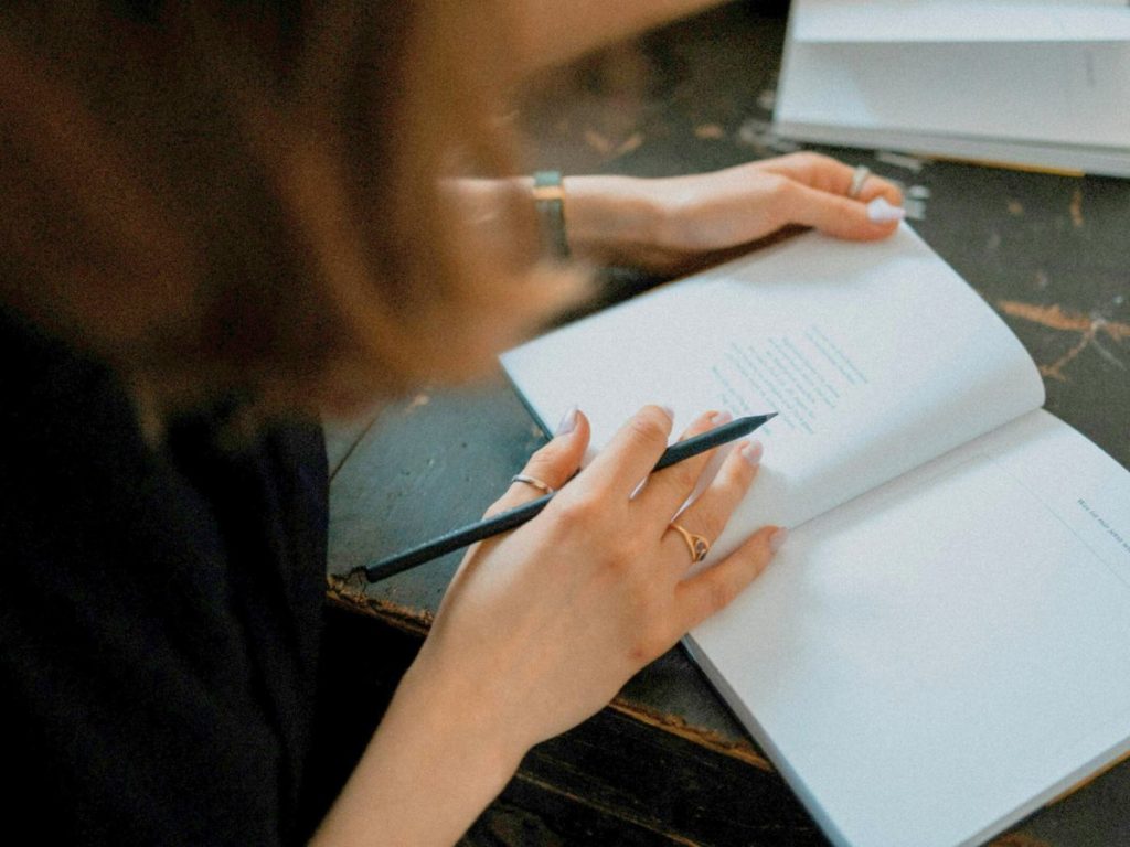 女性がノートに何かを書き網としている写真