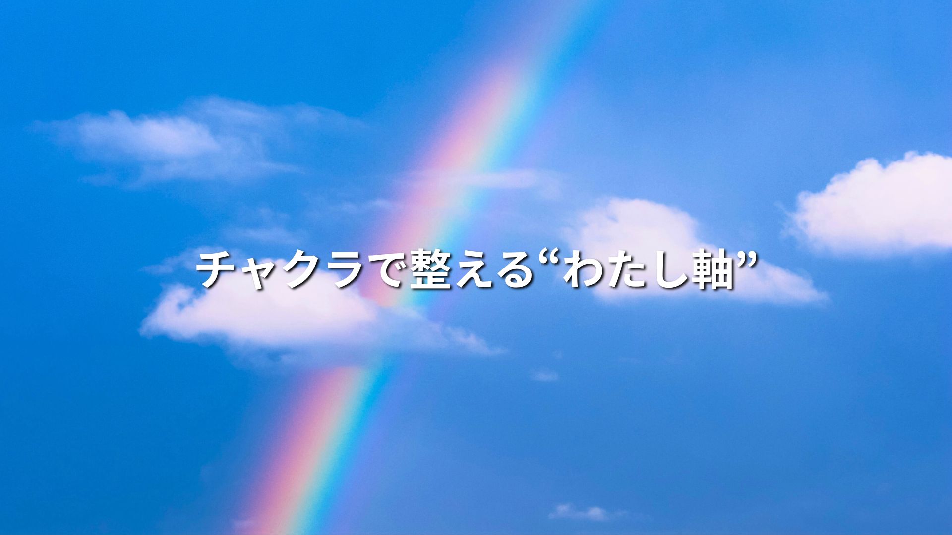 白い雲が浮いている空に、7色の虹がかかっている画像